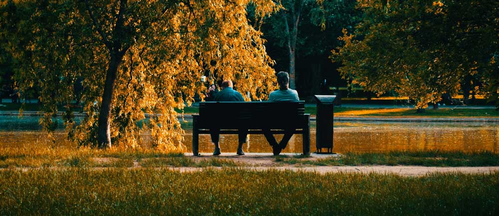 Two people sitting on a bench in a park